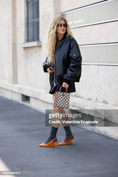 Emili Sindlev is seen ahead of the Prada fashion show wearing a Prada bomber jacket, orange shoes and black skirt during the Milan Fashion Week S/S...