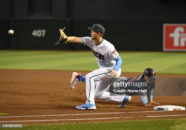 Pavin Smith of the Arizona Diamondbacks catches a throw from pitcher Merrill Kelly as Jose Miranda of the Minnesota Twins dives safely back to first...