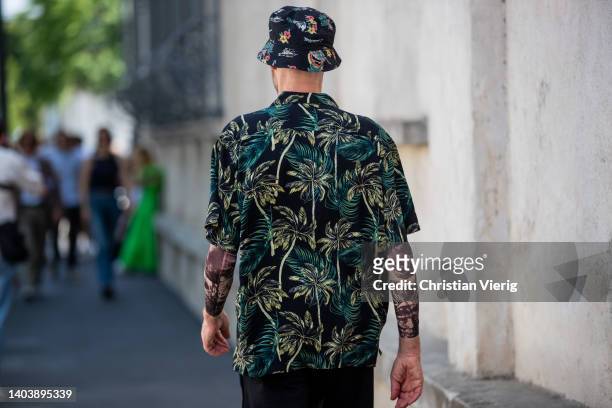 Raimondo Rossi is seen wearing bucket hat, button shirt with floral print black green and a guest wearing blue polo shirt, navy pants outside of...
