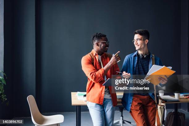 zwei glückliche freunde, die sich unterhalten und spaß in der bibliothek haben - two men studying library stock-fotos und bilder