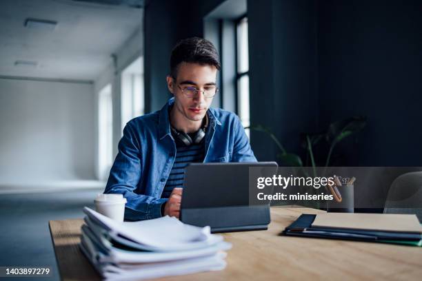 university student studying online on his digital tablet in the library - confident desk man text space stock pictures, royalty-free photos & images