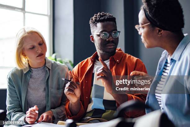 three friends studying together in the library - gender diversity stock pictures, royalty-free photos & images