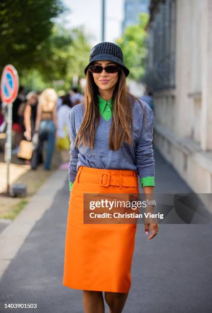 Tamara Kalinic seen wearing grey sweater, orange skirt, Prada bucket hat, bag with pattern, heels, sunglasses outside Prada of during Milan Fashion...