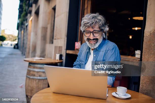 mature man on a journey enjoying at the cafe and making a video call - barcelona cafe stock pictures, royalty-free photos & images