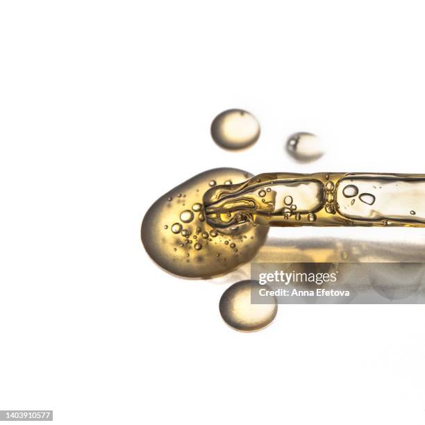 glass pipette spilling drops of moisturizing lotion on white background. polyglutamic acid is new hyaluronic acid. macro photography - argan oil stock-fotos und bilder