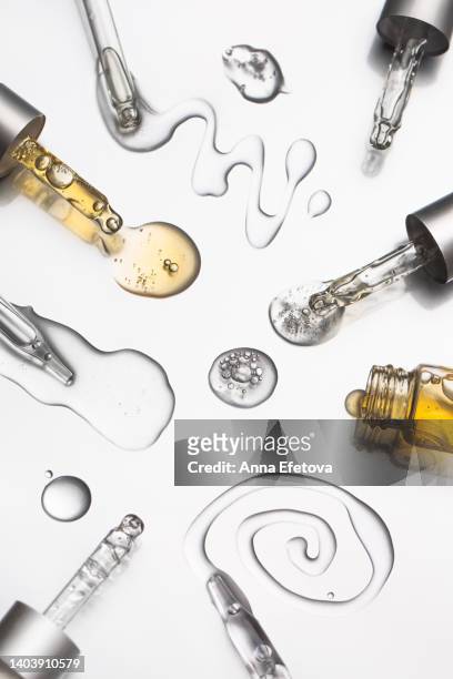 many glass pipettes spilling drops of different moisturizing lotions on luxury silver background. polyglutamic acid is new hyaluronic acid. macro photography - chemical products stock pictures, royalty-free photos & images
