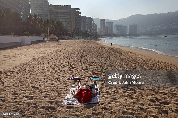 Lone tourist lies out on the beach early on March 2, 2012 in Acapulco, Mexico. Drug violence surged in the coastal resort last year, making Acapulco...