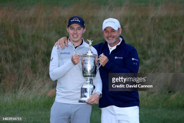 Matthew Fitzpatrick of England holds the trophy with his caddie Billy Foster after his one shot victory in the final round of the 2022 U.S.Open at...