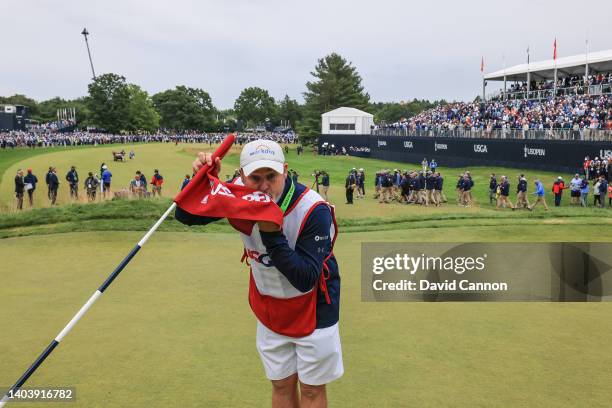 Billy Foster of England the caddie of US Open Champion Matthew Fitzpatrick kisses the flag on the 18th green after Fitzpatrick's one shot victory in...