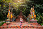 Young woman walking up the stairs of the temple, Doi Suthep in Chiang Mai, Thailand.