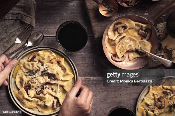 handmade mushroom and truffle cheese ravioli, human hands holding plate - sahnesoße stock-fotos und bilder