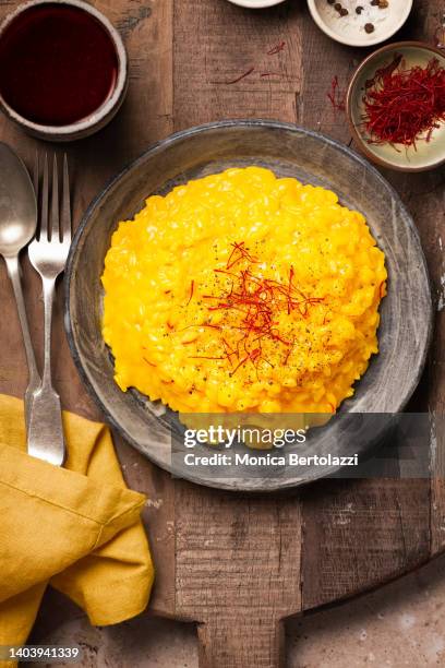 saffron risotto on rustic wooden table with red wine glass - saffron stock pictures, royalty-free photos & images