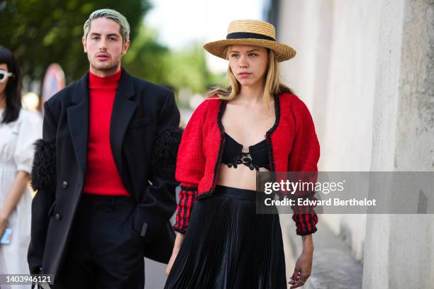 Alejandro Acero wears a neon red high neck wool pullover, a black oversized blazer jacket with large embroidered feathers yoke on the sleeves from...