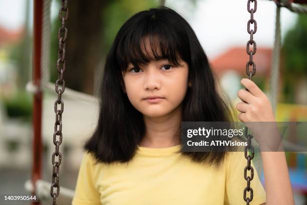 front view portrait mental illness child tween girl sitting on the swing and looking at the camera. disruptive - jj girls stock pictures, royalty-free photos & images