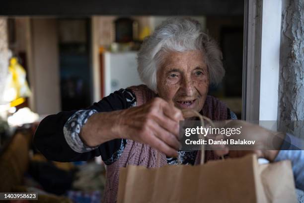 junge freiwillige, die einer älteren frau zu hause essen liefert. - meals on wheels stock-fotos und bilder