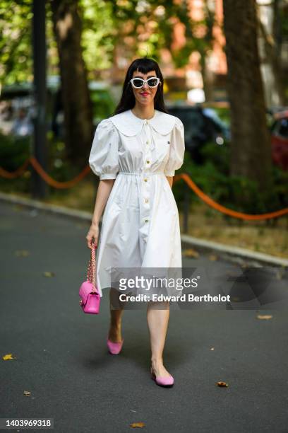 Guest wears white sunglasses, a white puffy short sleeves / shirt neck / buttoned midi dress, a pink shiny leather quilted mini Timeless handbag from...