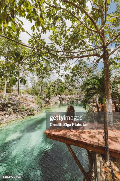woman sitting on a dock in cenote - riviera maya mexico stock pictures, royalty-free photos & images