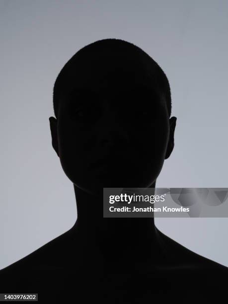 silhouetted female model against gray background - silhouettes stock-fotos und bilder