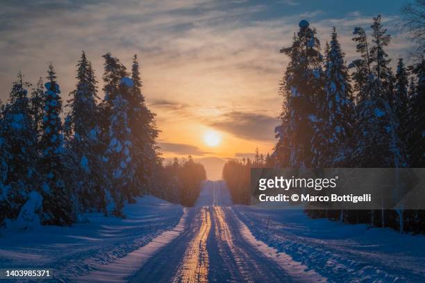 sunset over snowy road in winter, lapland - snowy mountain road stock pictures, royalty-free photos & images