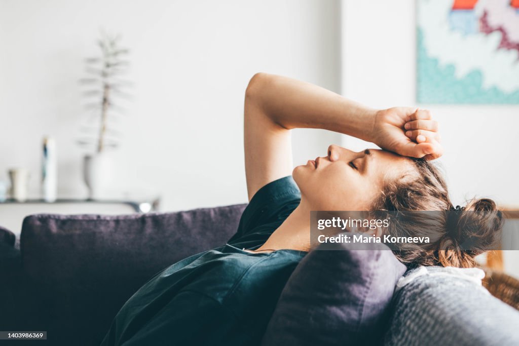 Sad and depressed woman sitting on sofa at home.