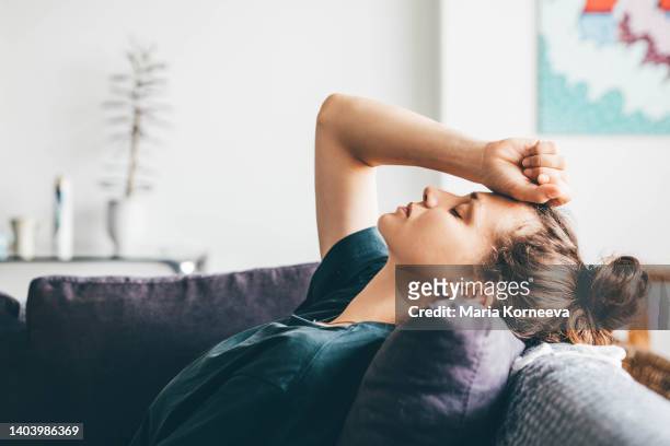 sad and depressed woman sitting on sofa at home. - frustração imagens e fotografias de stock