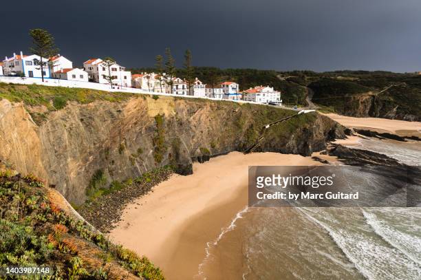 the setting sun illuminating the village of zambujeira do mar after a brief rainstorm along the rota vicentina hiking trail in southwest portugal - alentejo stockfoto's en -beelden