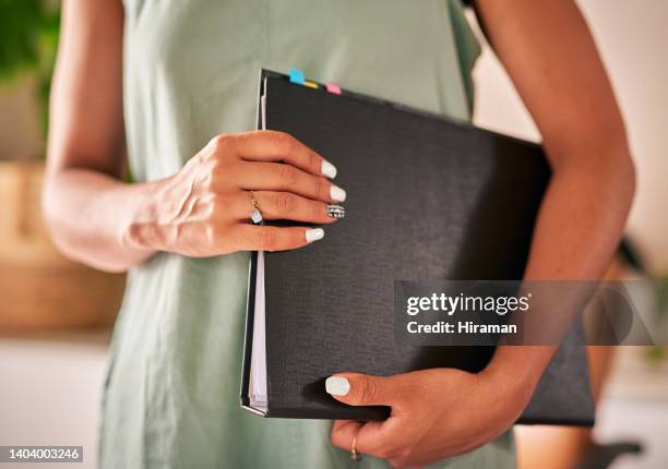 closeup of one female torso holding a file in her arms at the office. mixed race businesswoman ready to discuss her business ideas. innovative entrepreneur design firm. - will files stock pictures, royalty-free photos & images