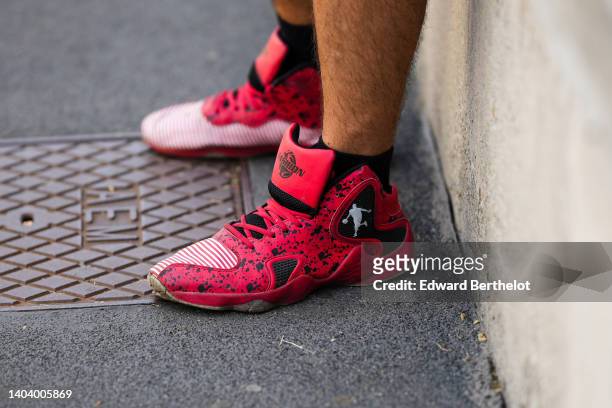 Guest wears red and black print pattern ankle sneakers from Jordan, outside the Prada fashion show during Milan Fashion Week Menswear S/S 2023 on...