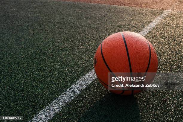 outdoor basketball court in the courtyard. a basketball is lying on the ground, on a sunny summer day. the concept of sports and a healthy lifestyle. copy space. - basketball court floor stock pictures, royalty-free photos & images
