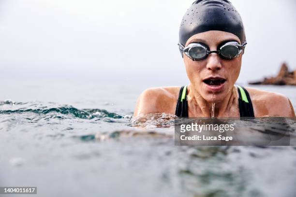 female swimmer in ibiza, wearing goggles and swim cap - triatlón fotografías e imágenes de stock