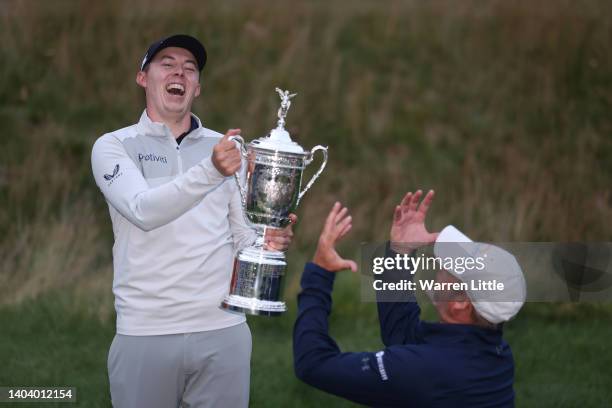 Matthew Fitzpatrick of England poses with the trophy as caddie Billy Foster congratulates him after winning the 122nd U.S. Open Championship at The...