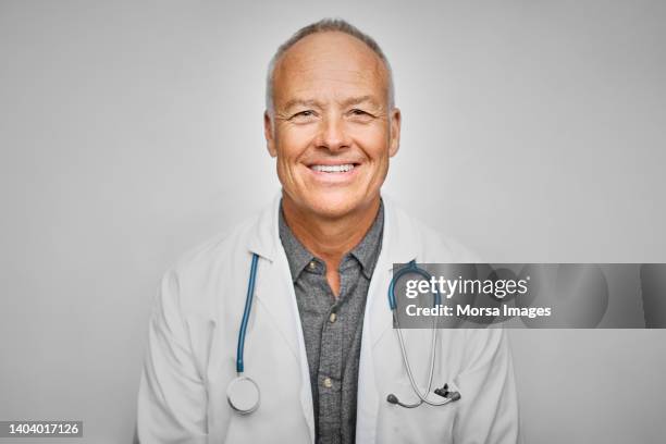 senior doctor smiling over white background - doctor looking at camera stock pictures, royalty-free photos & images