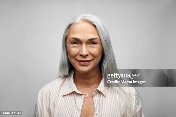 mature businesswoman smiling on white background - white hair stock-fotos und bilder