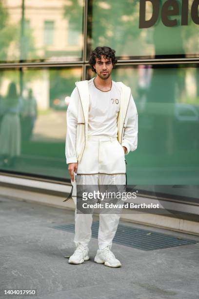 Yanis Serbout wears silver earrings, a white latte cut-out pattern t-shirt from Emporio Armani, a white latte / pale yellow cut-out pattern zipper...