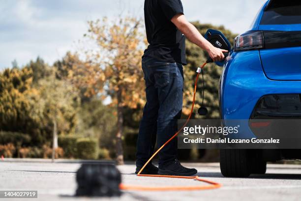 unrecognizable man charging electric car - 蓄電池 ストックフォトと画像