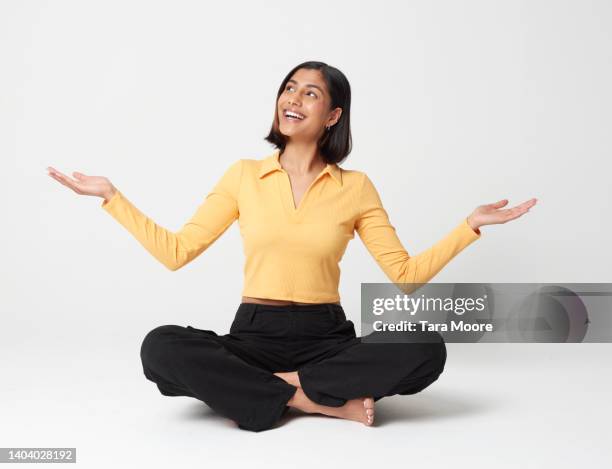 woman crossed legged with hands out - woman relaxed portrait sitting stockfoto's en -beelden