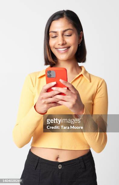 young woman looking at mobile phone - donna sorride cellulare foto e immagini stock