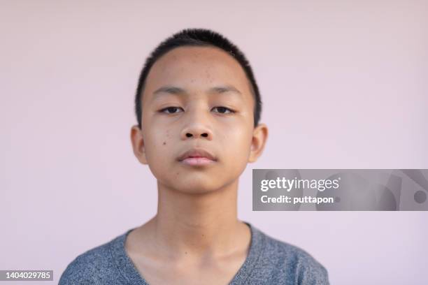 portrait of a asian boy in various moods and looking at the camera - stock photo - studio head shot serious confident looking at camera foto e immagini stock