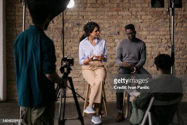 journalist, der verschiedene gruppen von schauspielern in einem studio interviewt - african american interview stock-fotos und bilder