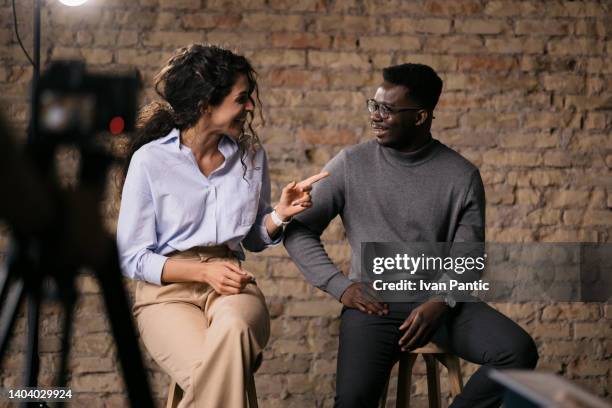 diverse couple of models giving an interview in a studio - press conference cameras stock pictures, royalty-free photos & images