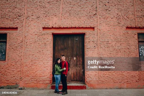 embraced heterosexual couple looking at the camera in front of a wooden door - lima perú fotografías e imágenes de stock