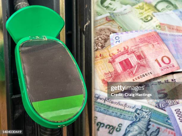 standard petrol gas station pump alongside a selection of foreign currency forex fiat banknote bills. concept piece for expensive rising gas prices due to inflation hyperinflation and the cost of living increase. - foreign affairs stock pictures, royalty-free photos & images