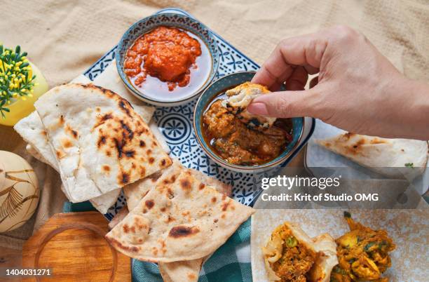 a hand dipping roti on the butter chicken - fried dough stock pictures, royalty-free photos & images