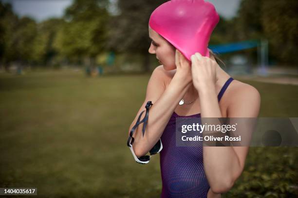 female swimmer putting on swimming cap - touca de natação - fotografias e filmes do acervo