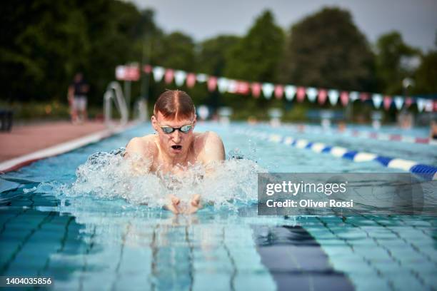 young man swimming breaststroke at an outdoor public swimming pool - コース�ロープ ストックフォトと画像