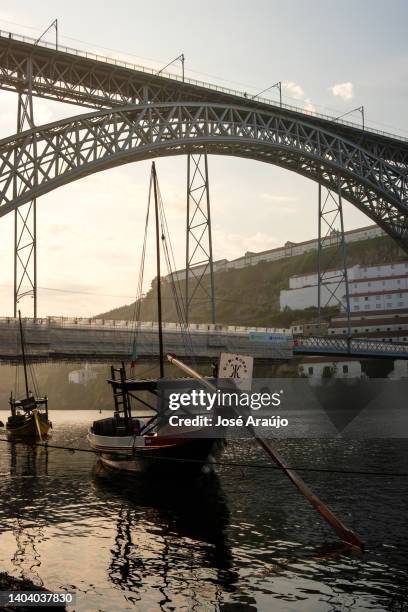 typical boat from ribeira in porto with the dom luis bridge behind - ribeira porto stock pictures, royalty-free photos & images