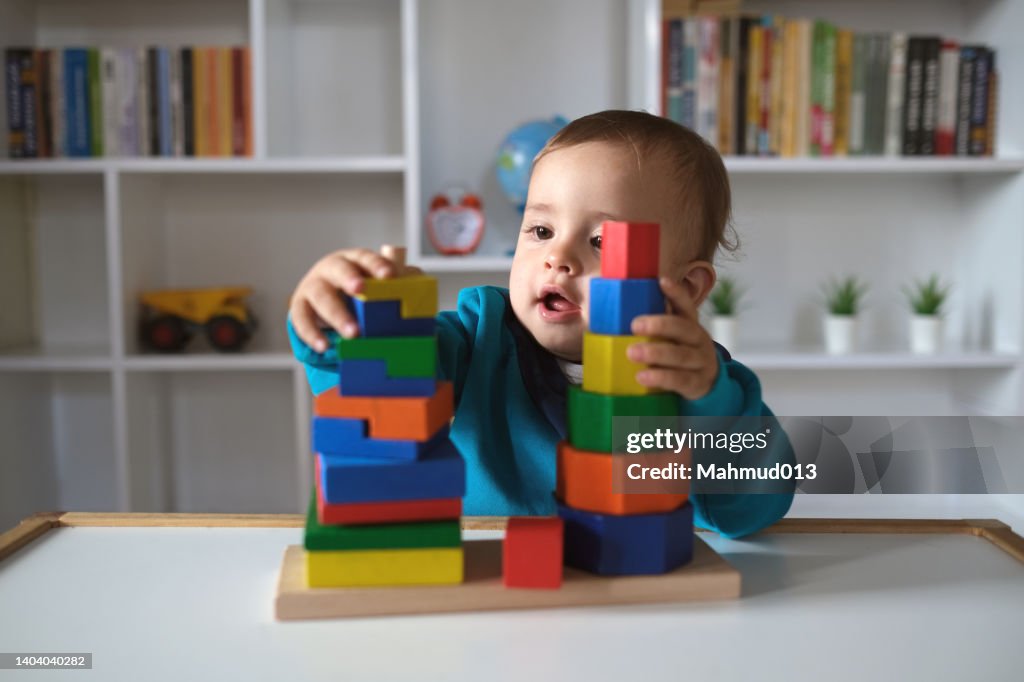 Niño nuevo jugando con juguetes de bloques de madera multicolores