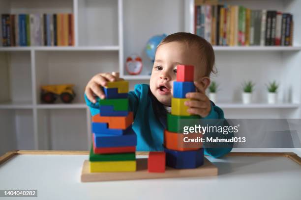 new boy playing with multi colored wooden block toys - daycare bildbanksfoton och bilder