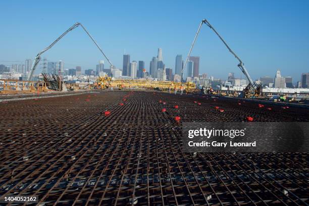 With the downtown skyline in the background a yellow concrete paver moves toward a wide span of rebar decking during the construction of the new 6th...