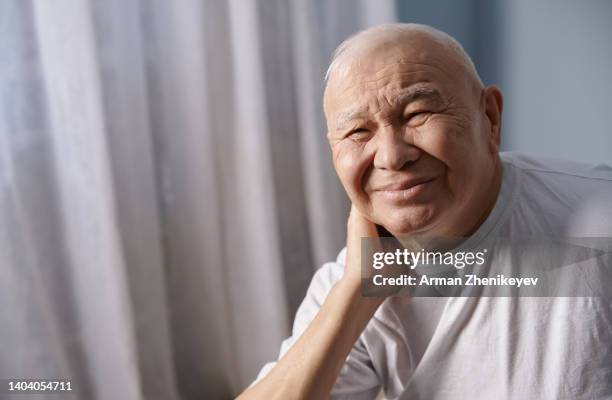 senior man at home suffering from neckhache - osteocyte stock pictures, royalty-free photos & images